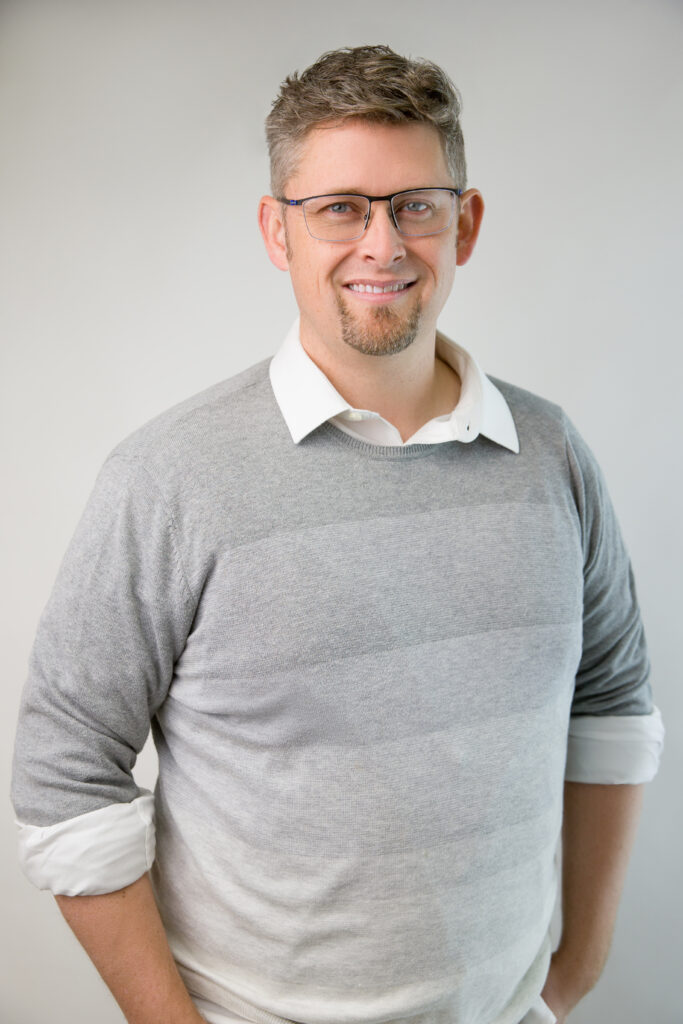 Sscramento headshot photography man in grey sweater with glasses and blue eyes. tech professional work wear