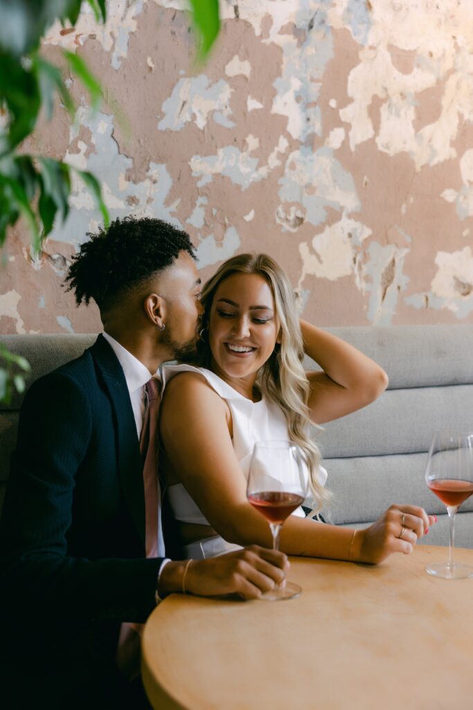 man whispering in woman's ear while drinking wine at a sacramento wine bar