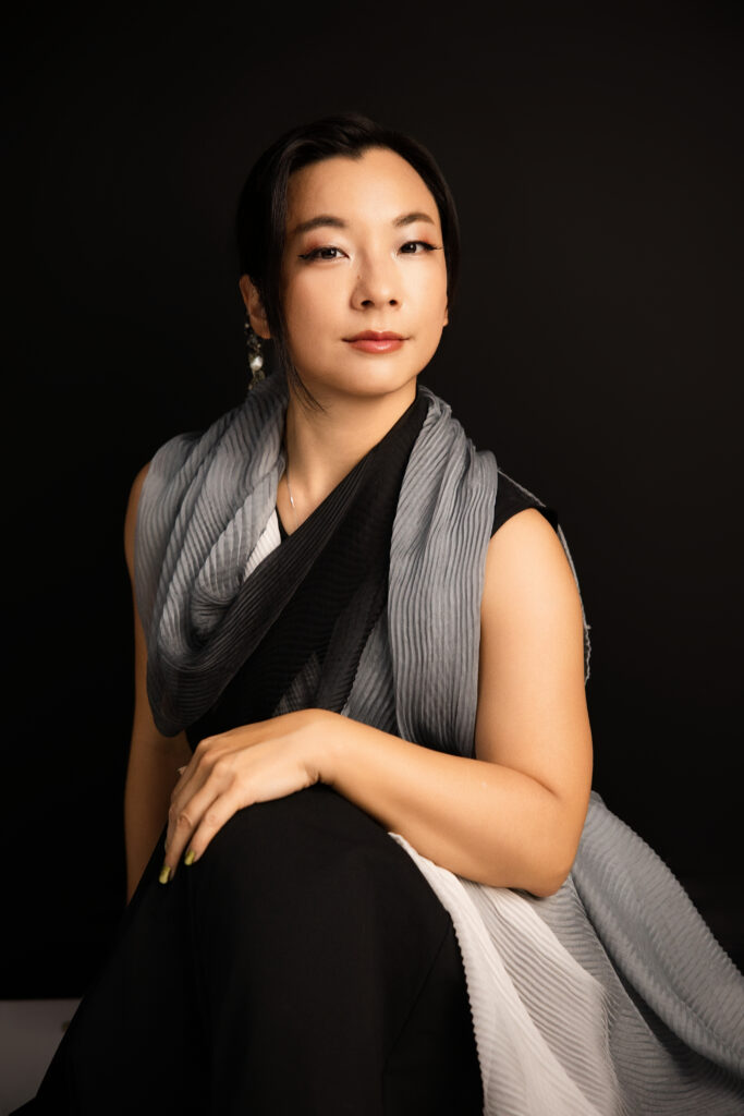 Woman sitting on the floor with legs crossed and smiling for editorial motherhood portrait experience