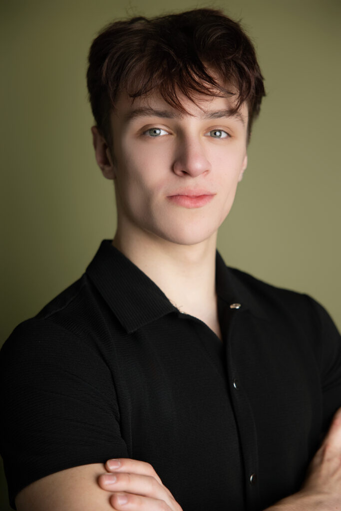 Editorial senior portrait of a teenage boy in a black shirt photographed with soft cinematic lighting in a modern Sacramento senior photography studio by Milou & Olin Collective.