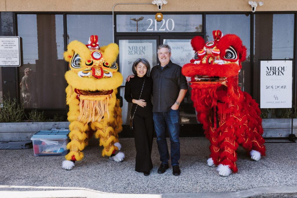Studio owners posing with traditional lion dancers during a cultural celebration outside a Sacramento photography studio at a grand opening event.