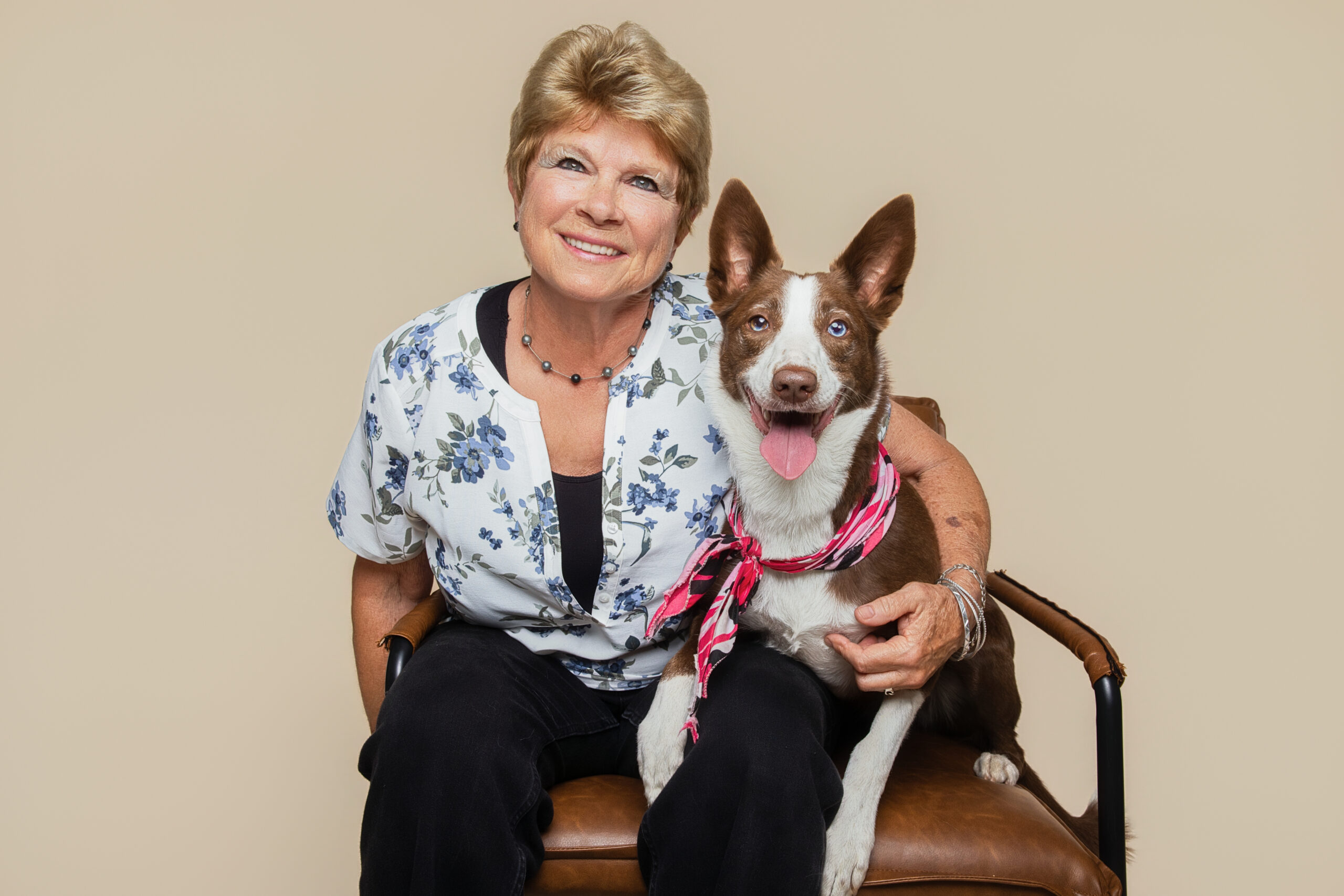 Pet portraits Sacramento featuring a smiling woman seated with her brown and white dog wearing a pink scarf, photographed by Pet Photos by Olin.